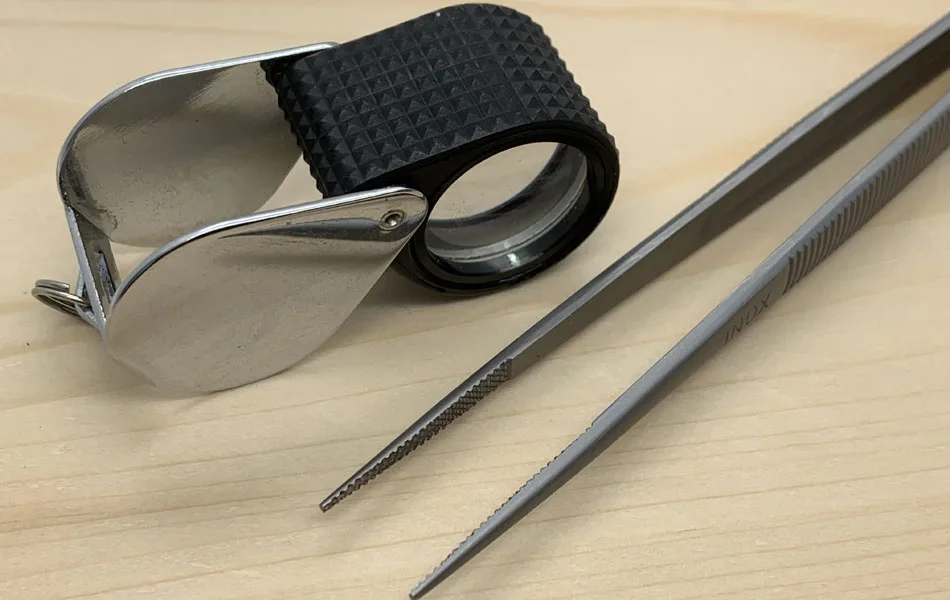 A jewelers loupe and tweezers